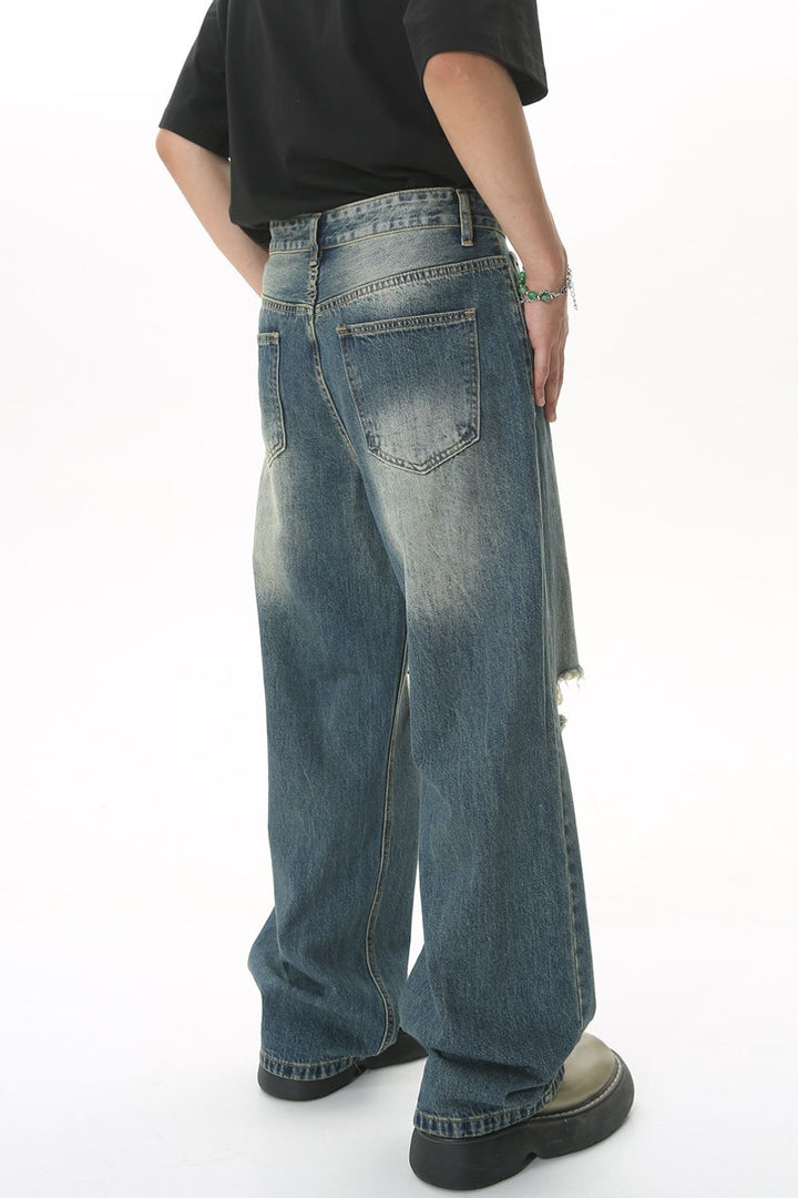 Back view of ripped and faded wide-leg jeans in blue vintage wash.