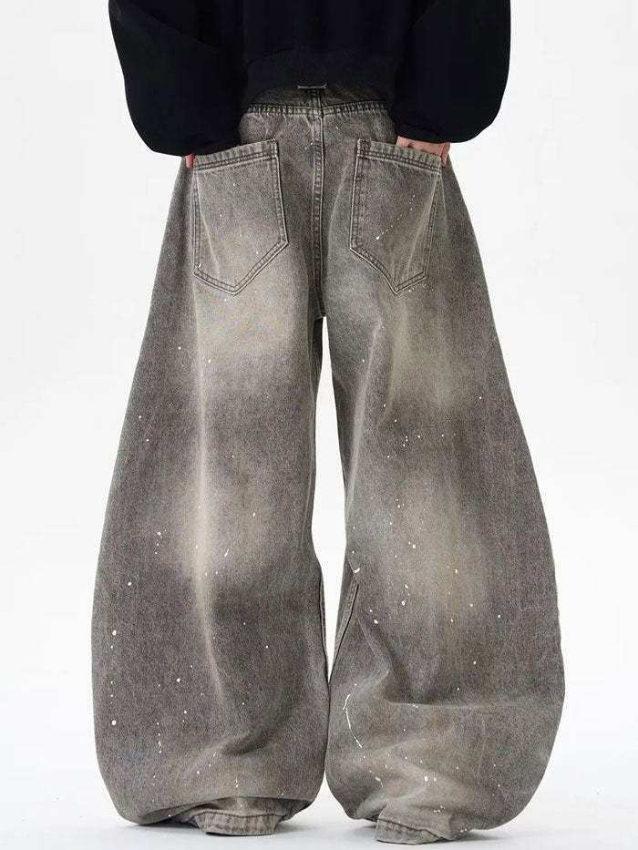 Back view of oversized grey denim jeans with patch pockets and splatter accents.