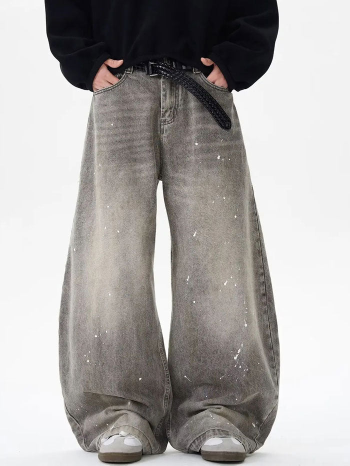 Front view of wide-leg grey jeans featuring a faded wash and paint splatter design.