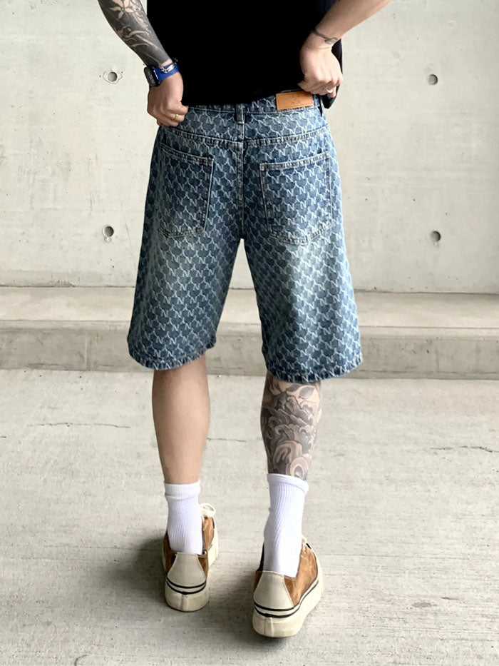 Back view of monogram denim shorts with vintage wash, worn by tattooed model