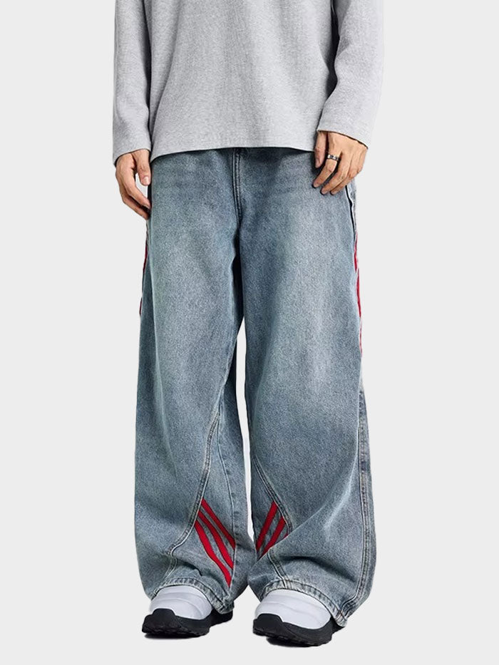 Front view of model wearing unisex baggy jeans with red diagonal stripes on a faded denim base.