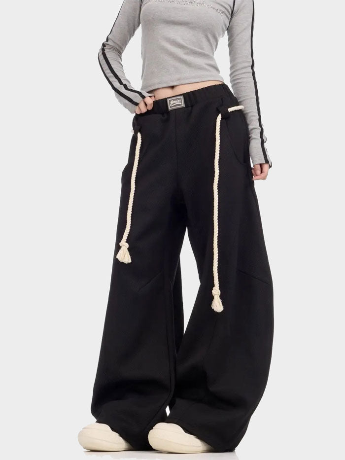 Midriff-revealing pose wearing black baggy rope-tie joggers and cropped top.