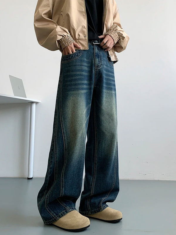 Man standing in vintage blue loose-fit jeans and beige jacket, casual streetwear style.