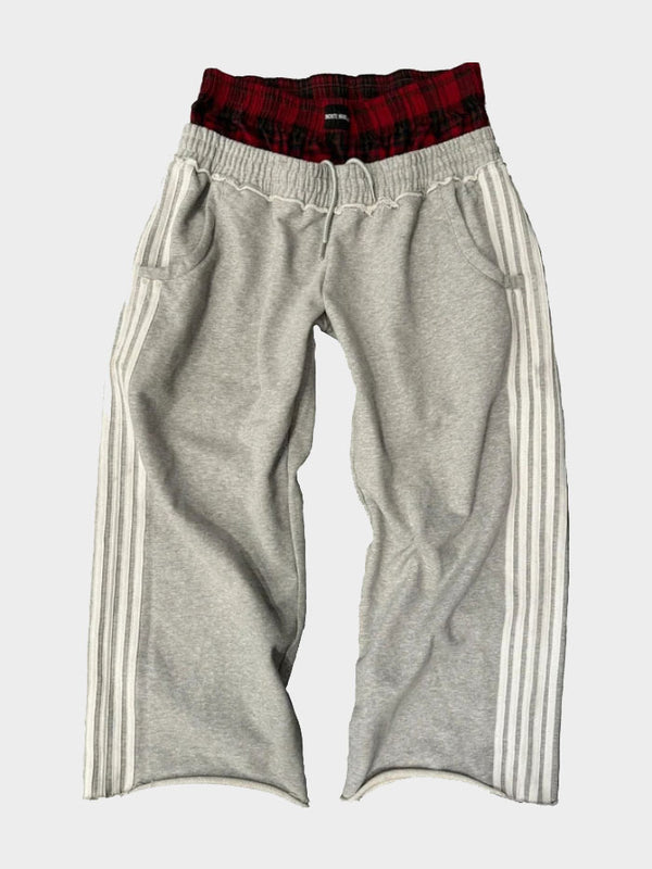 Grey jogger-style track pants featuring white side stripes and red plaid waistband design by Concrete Mans.