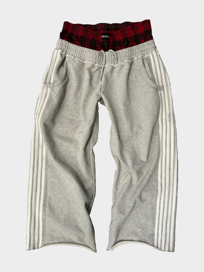 Grey jogger-style track pants featuring white side stripes and red plaid waistband design by Concrete Mans.
