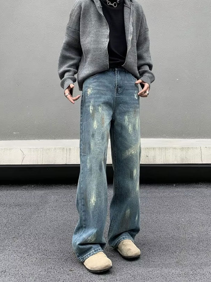 Distressed vintage jeans with faded patches worn in urban streetwear outfit.