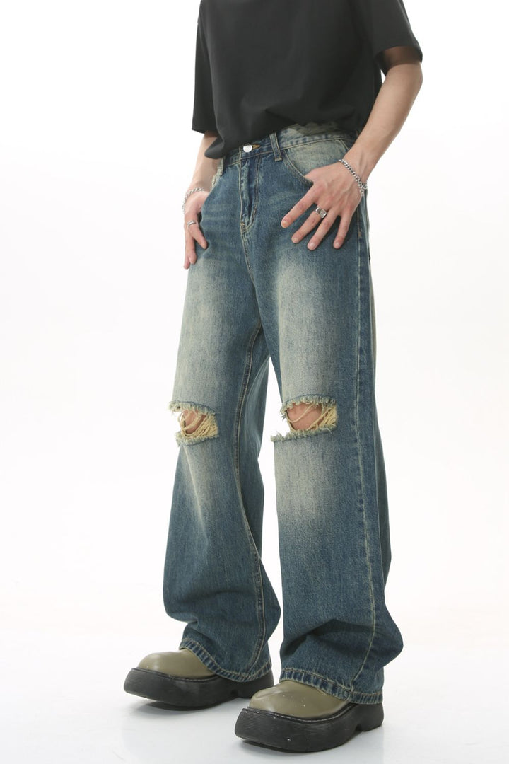 Model wearing street-style wide-leg jeans with heavy fading and ripped knees.