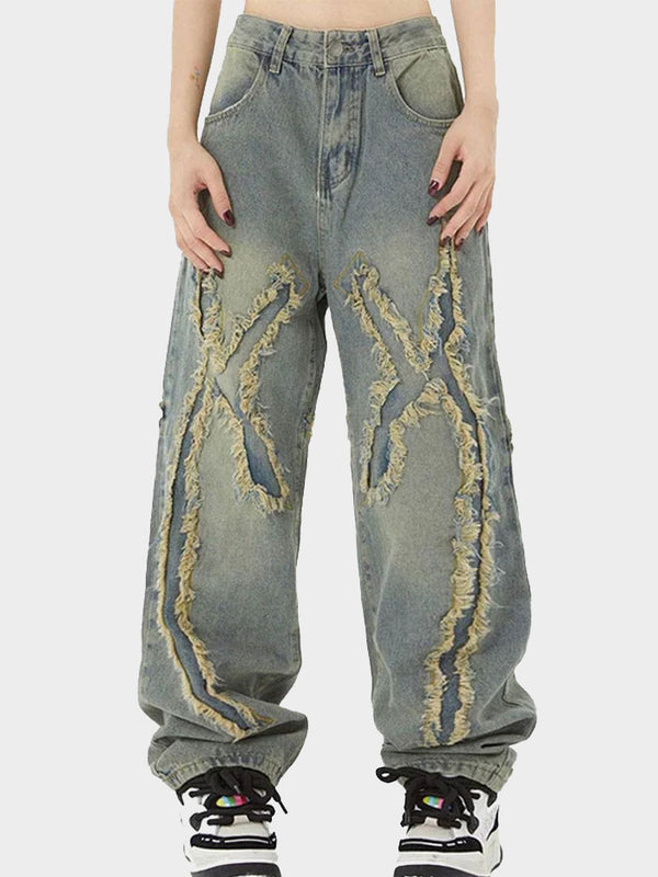 Close-up of X-shape frayed fringe detail on baggy washed denim jeans.