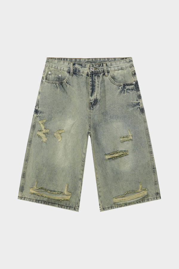Flatlay of distressed green denim shorts with multiple ripped accents and faded finish