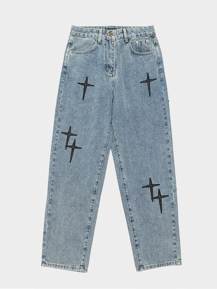 Front-facing view of light-wash baggy jeans featuring bold black cross patches.