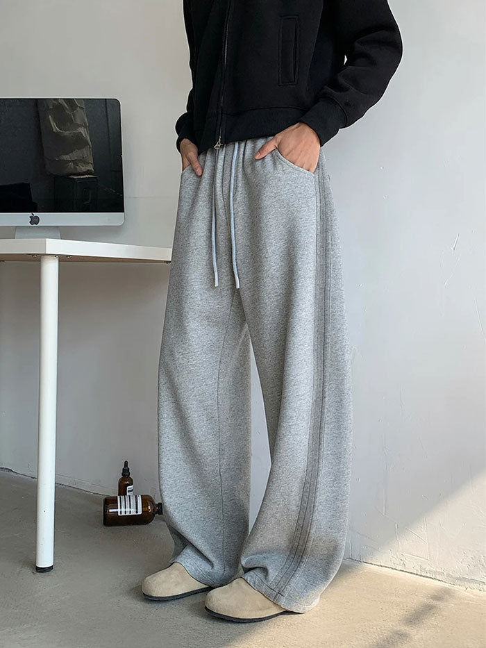 Side view of men’s grey oversized sweatpants with wide leg design.