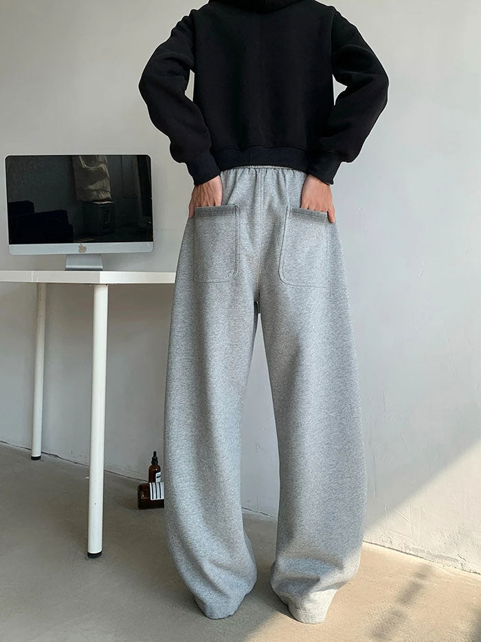 Oversized grey sweatpants with patch pockets, back angle.