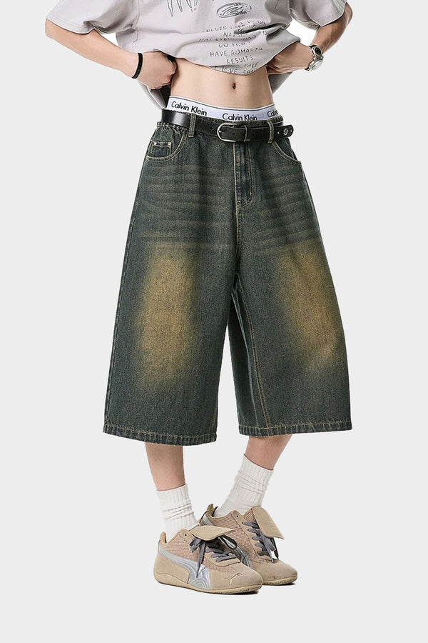 Front view of washed green wide denim shorts with grunge fade