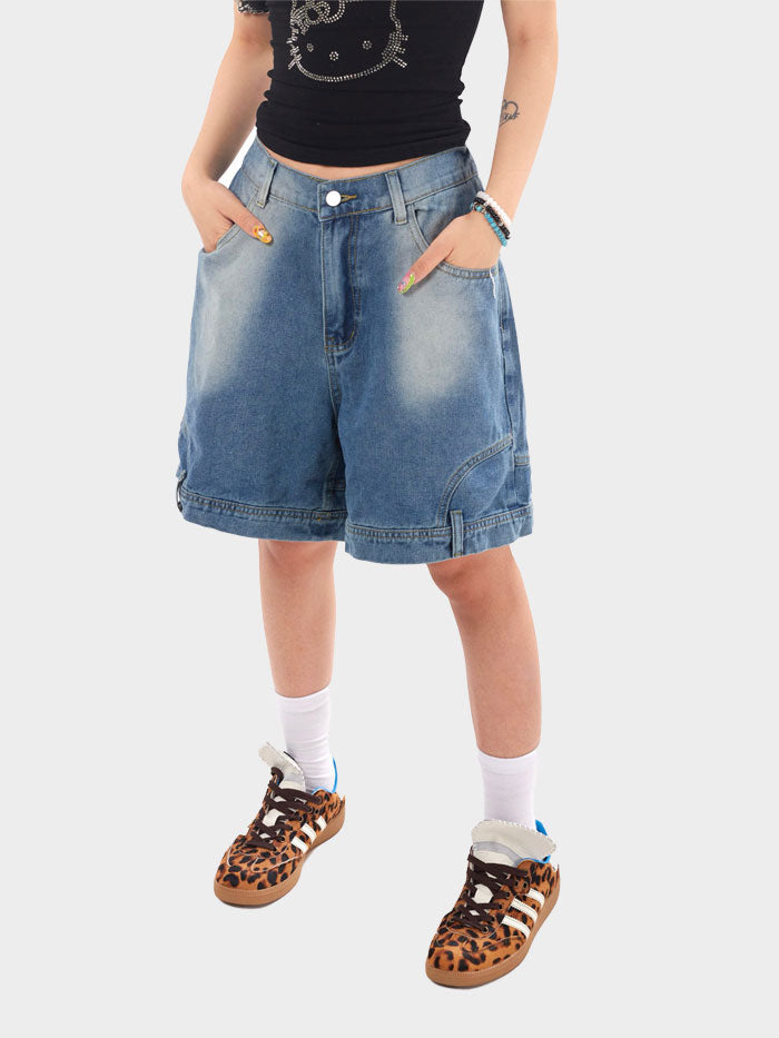 Model wearing light-wash denim shorts styled with a Hello Kitty tank and cheetah Adidas.