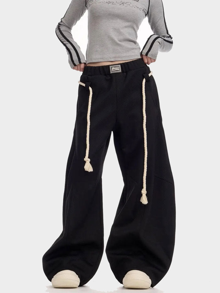 Black oversized sweatpants styled with rope drawstring belt and chunky sneakers.