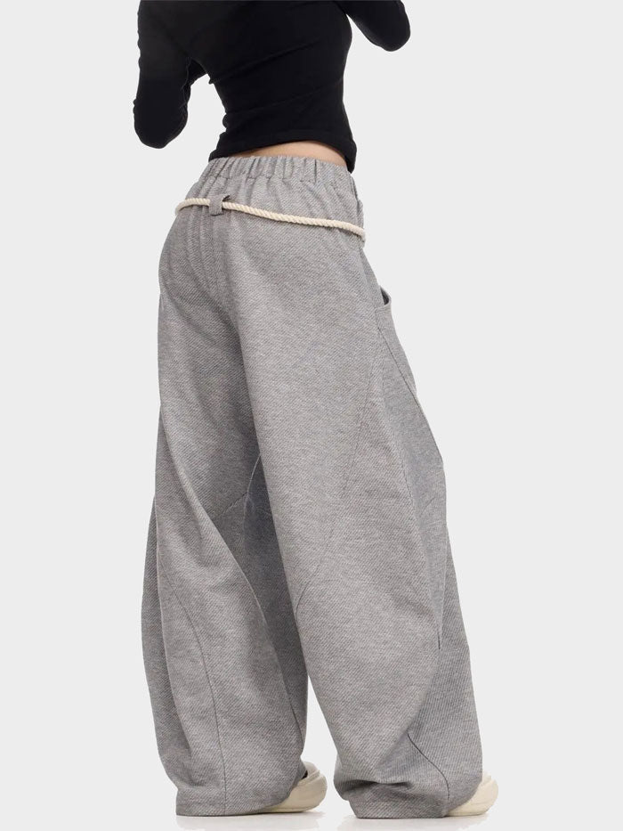 Back view of gray oversized sweatpants with unique side panel seams and rope belt.