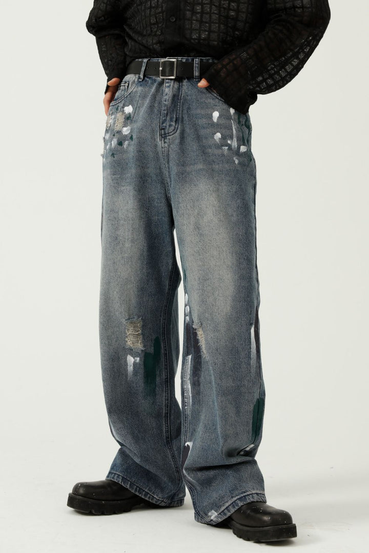 Front view of paint-splattered wide-leg jeans with distressed detailing