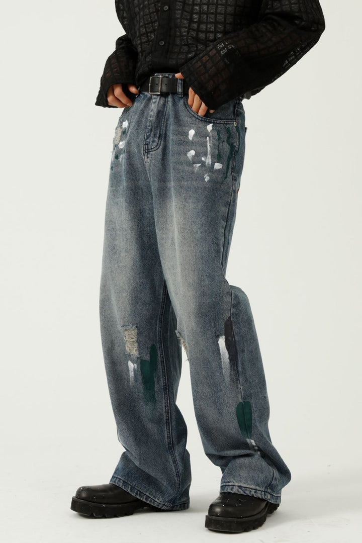 Model wearing oversized jeans with paint marks and casual streetwear vibe