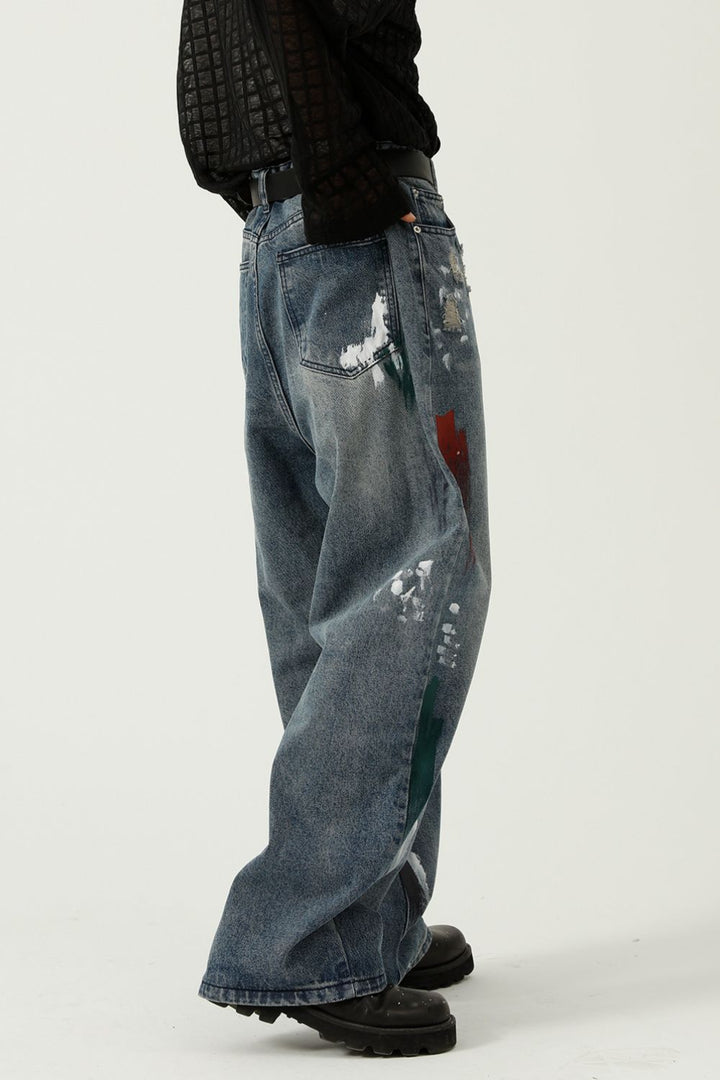 Urban fashion jeans featuring raw hem, faded wash, and artistic paint strokes