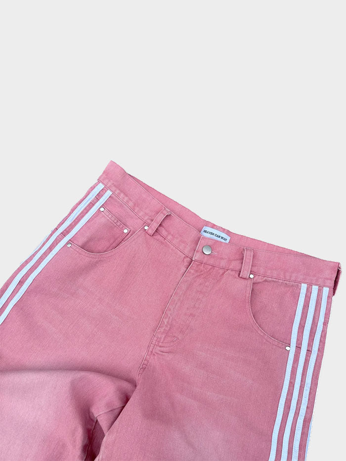 Close-up of pink denim jeans showing front pockets and white stripe detailing along the seams.