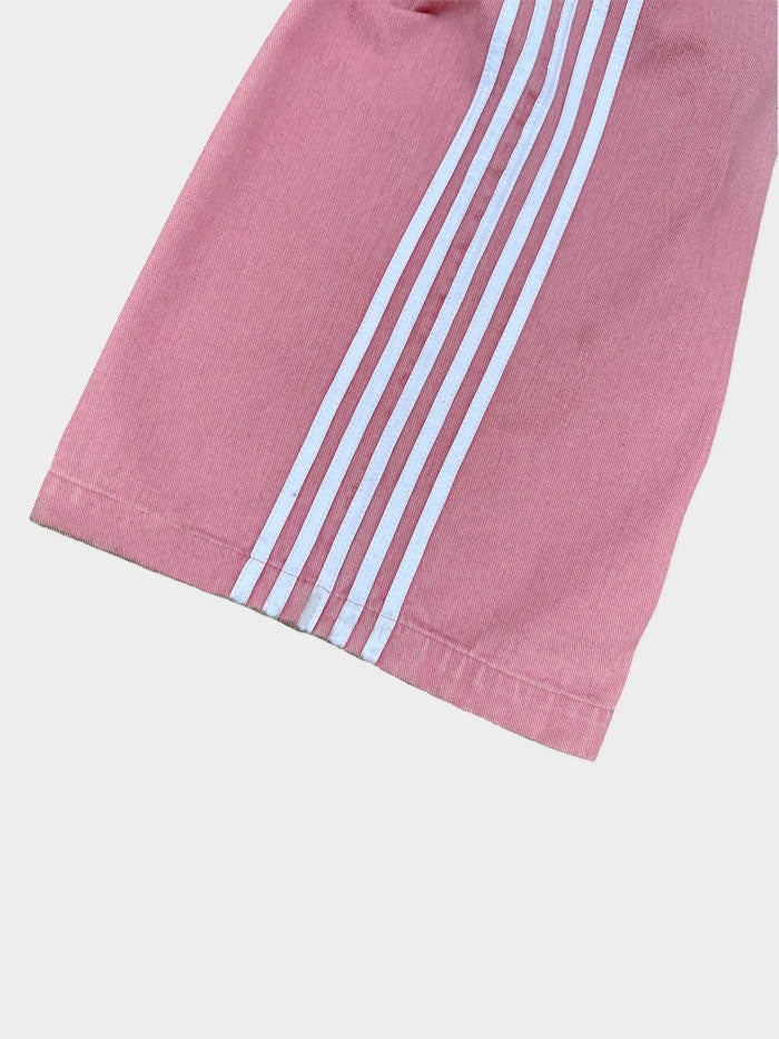 Detailed view of the lower leg area of pink jeans featuring bold white vertical stripes.
