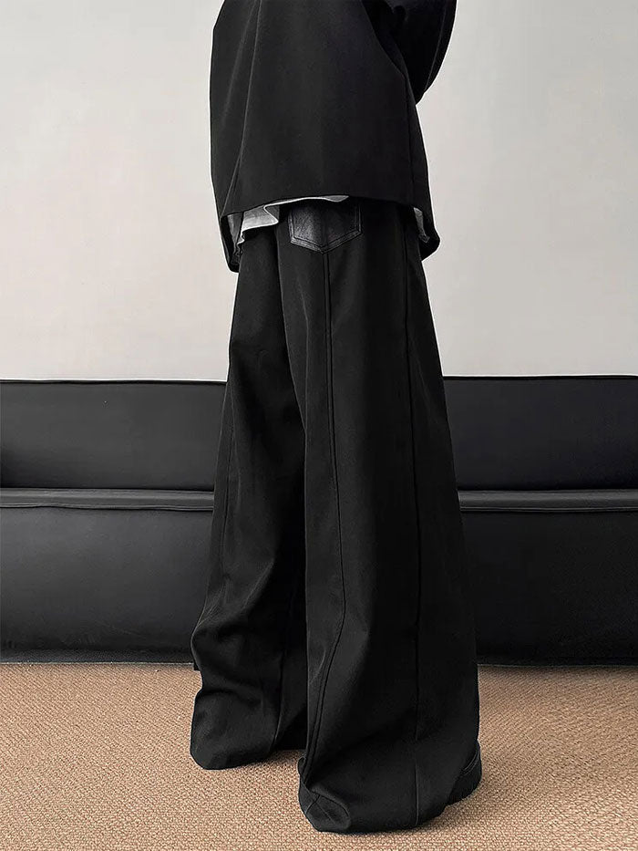 Angled view of black pants featuring oversized leather paneling with zip lines.