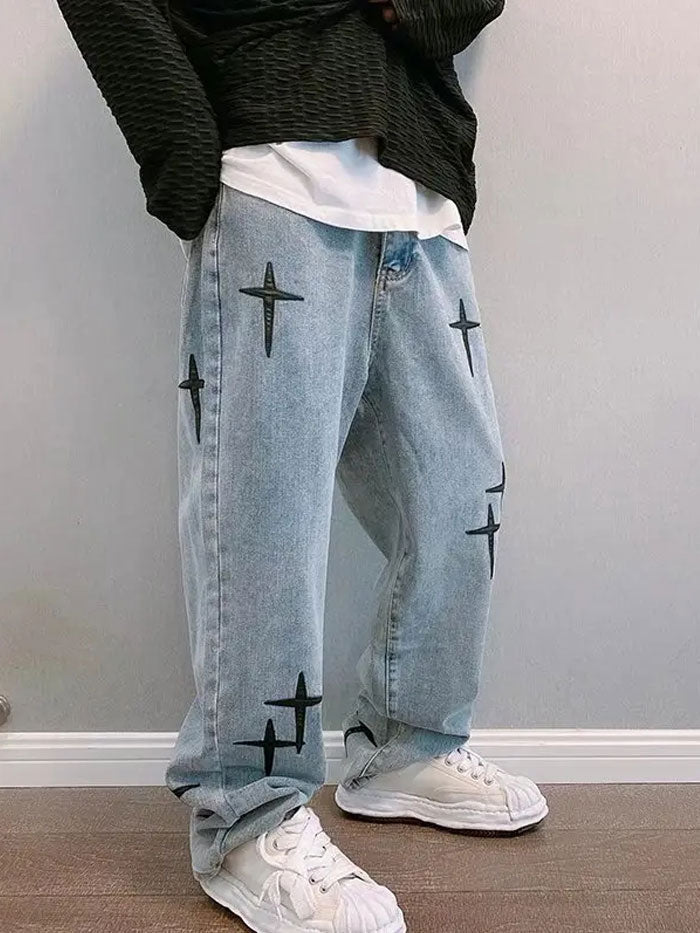Side profile of a model wearing trendy men's streetwear jeans with black cross designs.