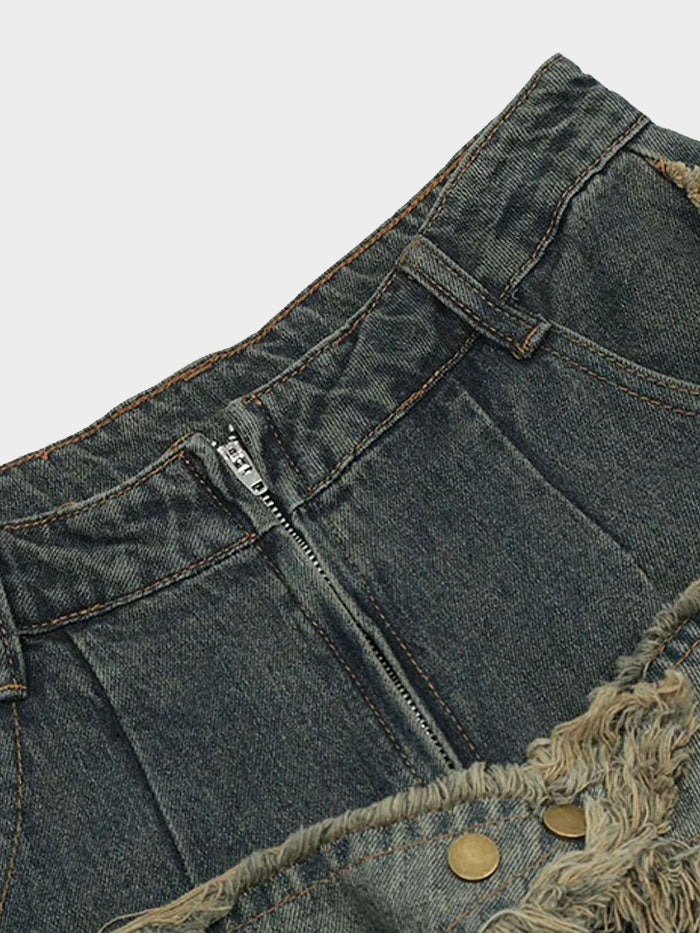Close-up of the waist and button detail on frayed star patch grunge jeans with vintage-style zipper closure.