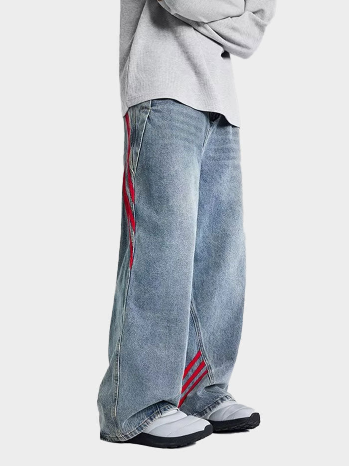 Side angle of unisex wide-leg jeans highlighting the bold red stripes and vintage wash.