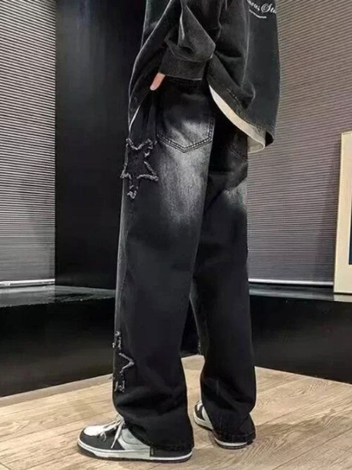 Rear view of black jeans featuring frayed star patches and a relaxed fit, paired with monochrome sneakers.