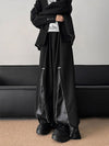 Front view of oversized black pants with full-length zipper leather detailing.
