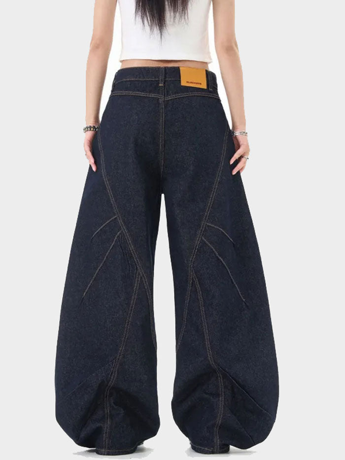 Angled front view of wide-leg dark denim jeans featuring button-up detail along both legs.