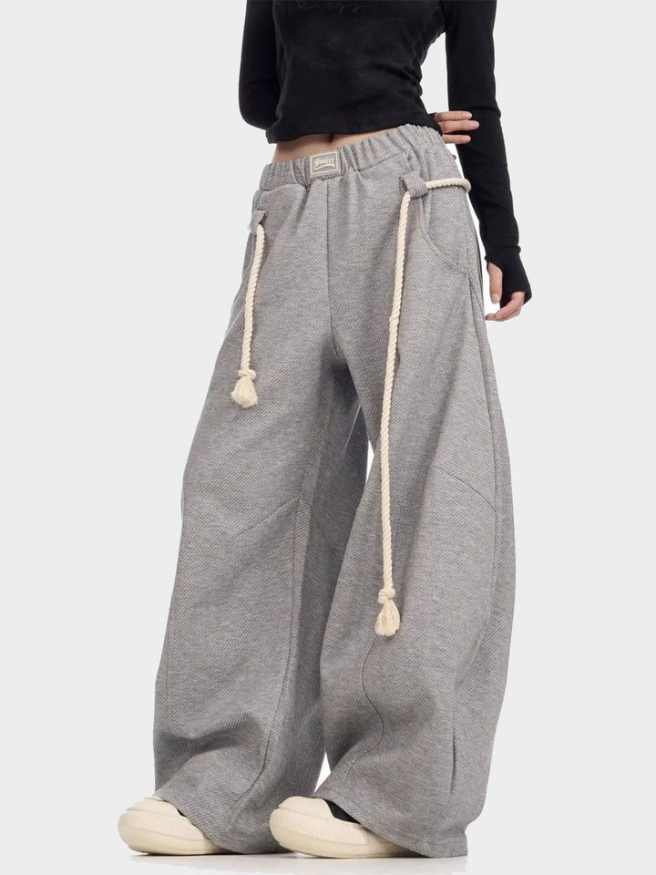 Side angle of gray wide-leg joggers with long drawstring detail and relaxed fit.
