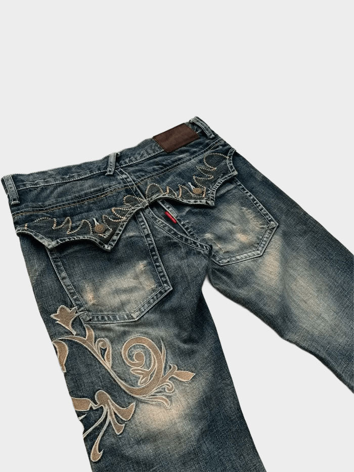 Close-up of back pocket embroidery and faded wash on flared denim jeans.